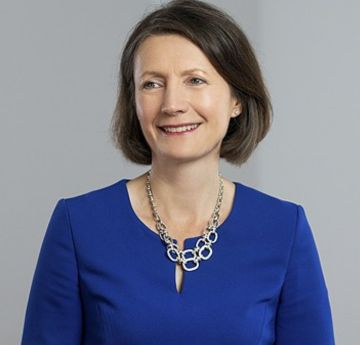 Menyw mewn gwisg glas yn gwenu wrth y camera