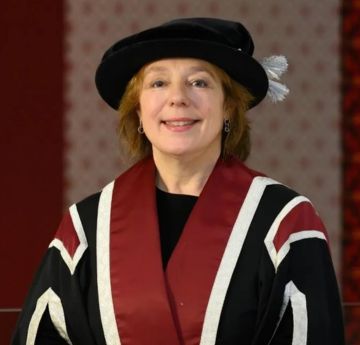 Lady in a cap and gown smiling at the camera