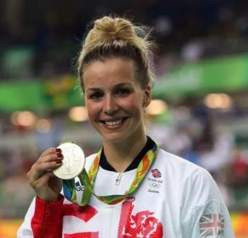 Menyw yn dal medal arian olympaidd ac yn gwenu i'r camera