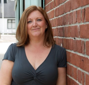 Menyw yn edrych at y camera yn gwenu