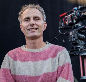 Dyn mew crys gwyn a pinc yn gwenu i'r camera