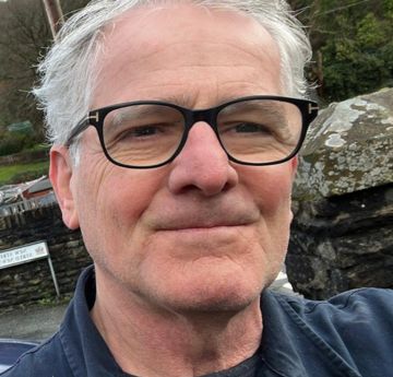 Dyn gyda sbectol yn gwneu i'r camera