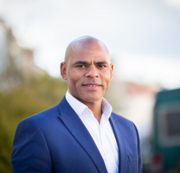 Dyn mewn crys yn gwenu i'r camera