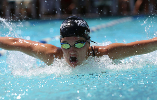 Mudferwi gyda het nofio ddu a gogls yn nofio mewn pwll