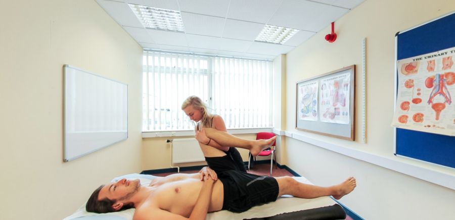 Ystafell driniaeth osteopathig gydag asesiad symudedd coes ar fwrdd triniaeth