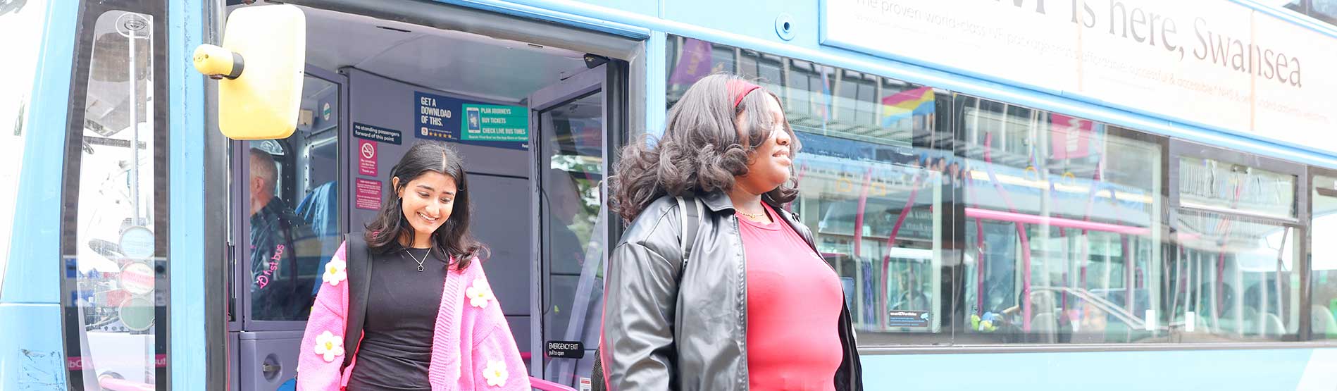 Two female students getting off a First Cymru bus on Singleton Campus at Swansea University