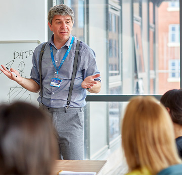 Darlithwr yn cyflwyno i ddosbarth o fyfyrwyr