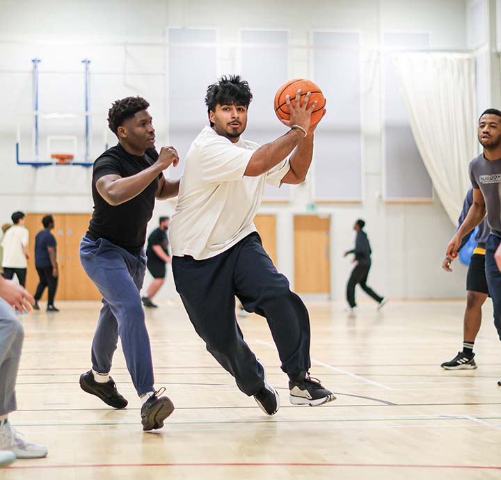 A group of students playing basketball in the sports hall