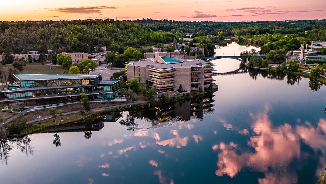 Trent University campus in Summer. Reflections can be seen in the surrounding water. 