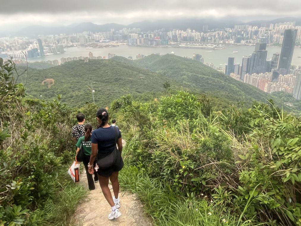 View of students hiking downwards with Hong Kong skyline in the background.