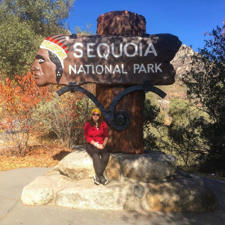 student in front of Sequoia national park sign