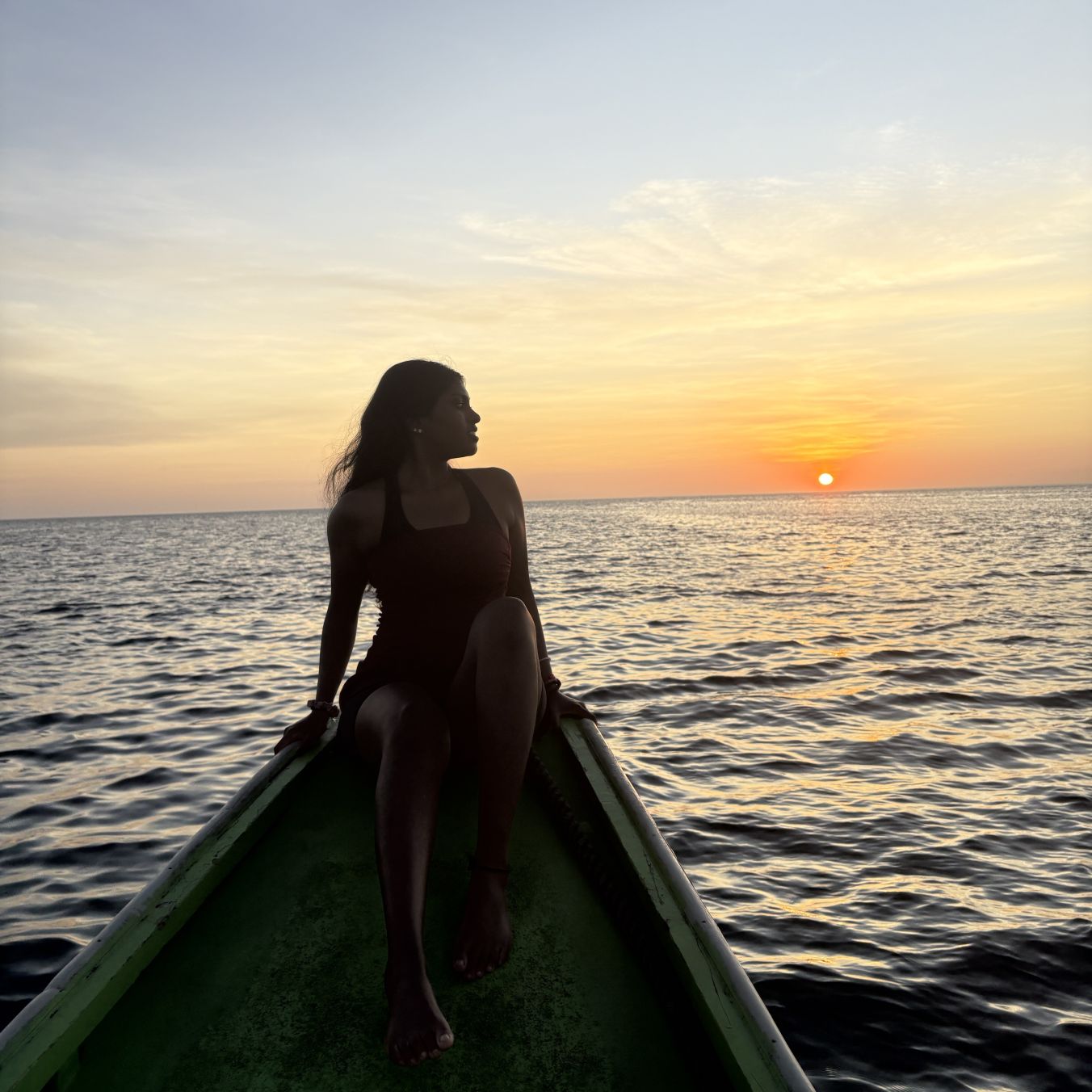 Student on boat in front of sunset