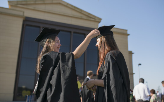 two girls preparing for a graduation ceremony