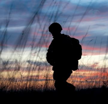 Silhouette of soldier marching cross-country