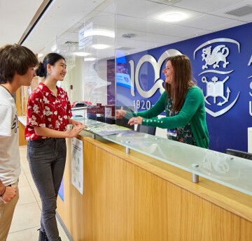 Students chatting to a member of staff at the reception