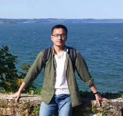 student smiling at the camera, standing in front of the sea