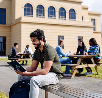 Swansea University student reading on Bay Campus