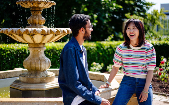Two studnets sitting by a fountain