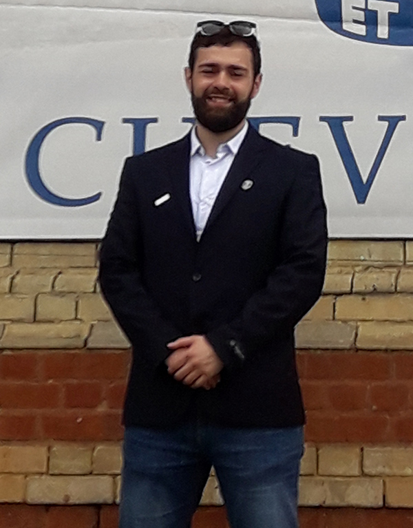 A student named Bilel standing in front of a Chevening banner