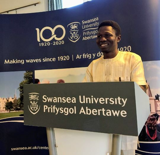 Photo of Nnadi Emmanuel Ebuka standing on a Swansea University podium 