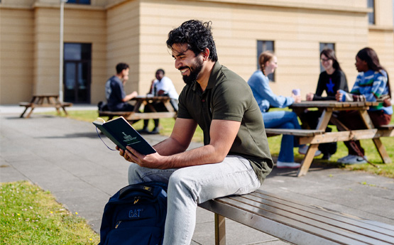 A man sitting on a bench reading a book