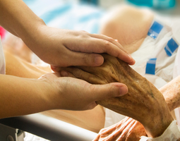 Young hand holding the hand of an elderly patient