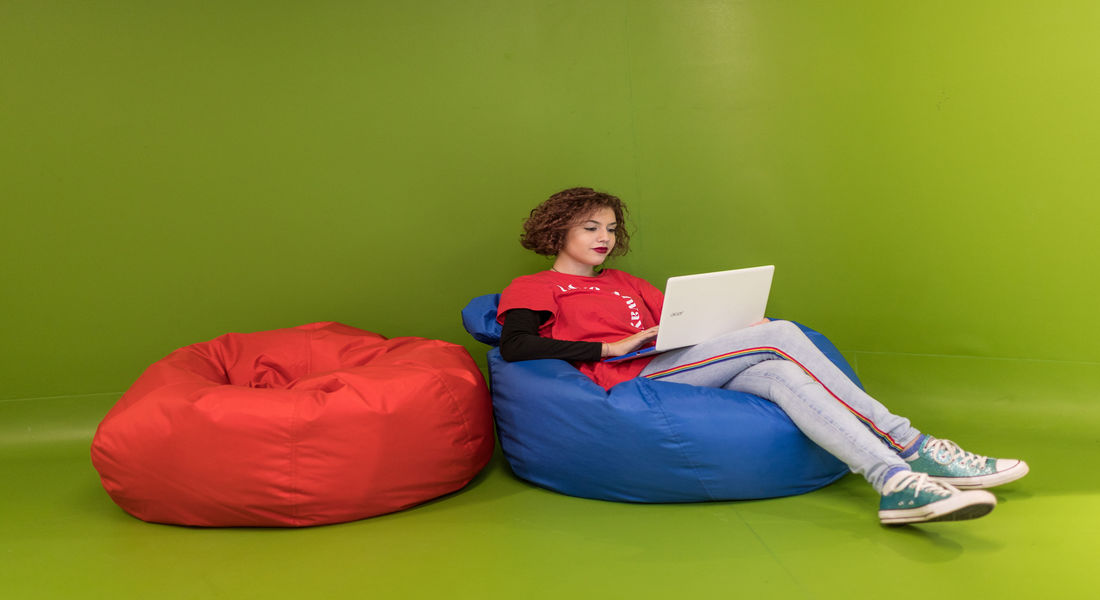 Female student working on laptop on bean bag.