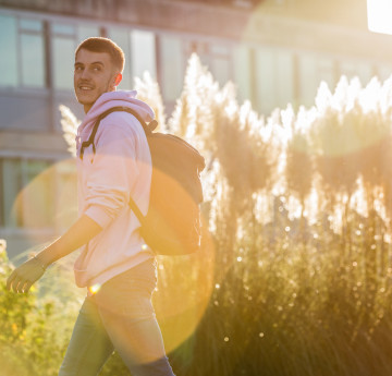 Male student walking in the sunshine.
