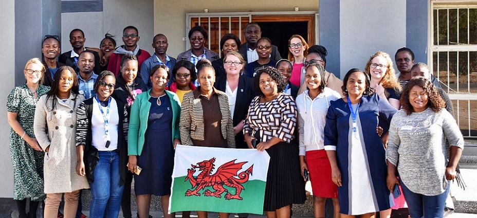 Group of Zambian students and Swansea staff holding a Welsh flag
