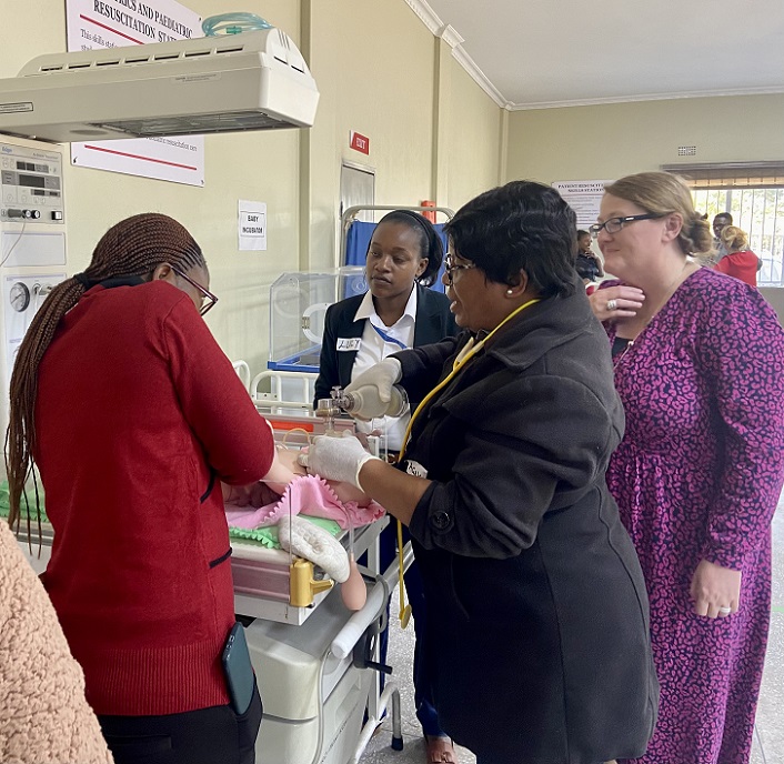 Students and instructor gathered around a neonatal resuscitation station