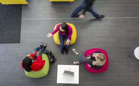 Three students sat on beanbags talking.