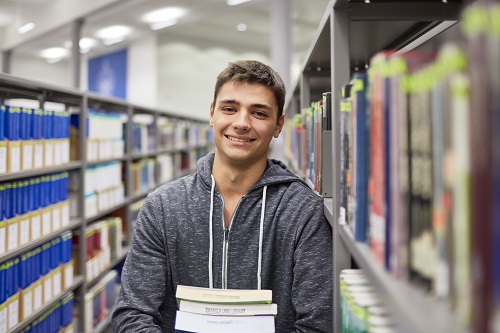 male holding books in a library 
