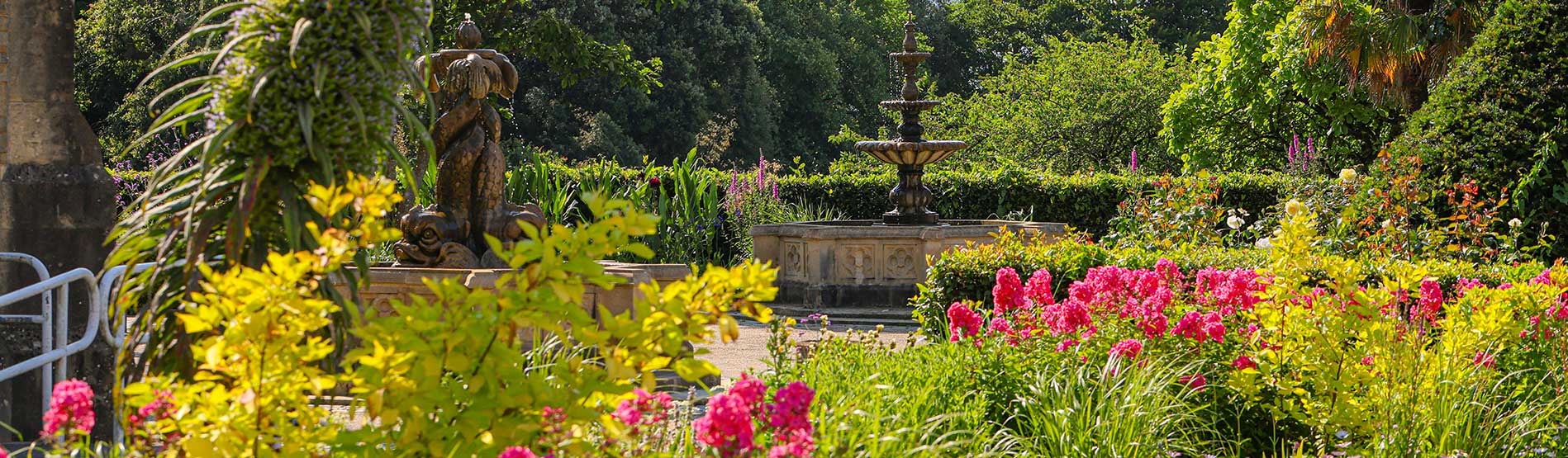 A fountain near Swansea University's historic Abbey Building and flowers in bloom in the foreground