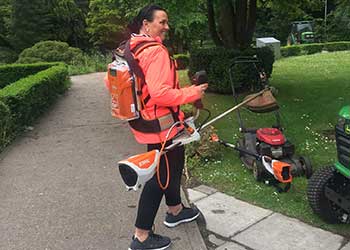 a grounds volunteer learning to use a strimmer