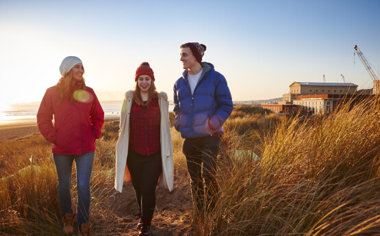 Students walking in sand dunes amongst reeds