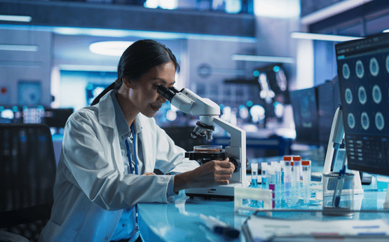 Student in lab coat examining specimen. 