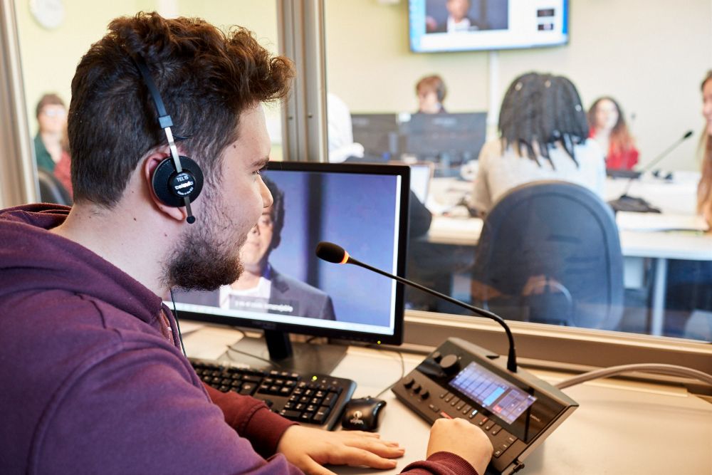 An image of a student working at a laptop wearing headphones.