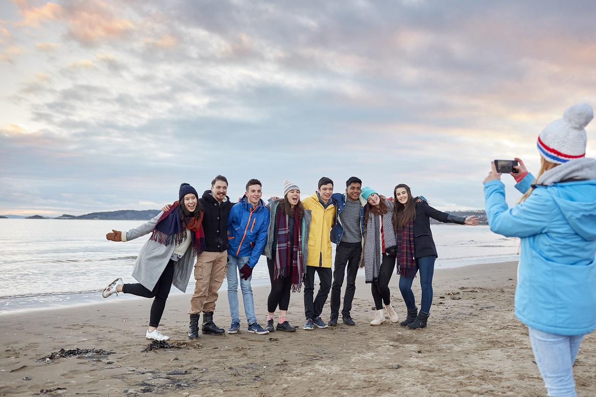 Group of males and females having their photo taken on a beach in winter