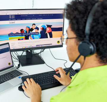 Student ambassador working at a computer wearing a headet for phone calls