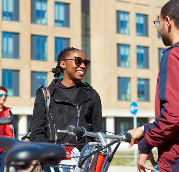 Two students outside Bay campus with bikes