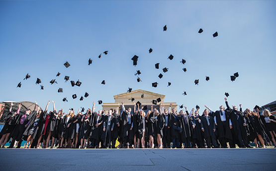 Graduates throwing their hats in front of the Great Hall.