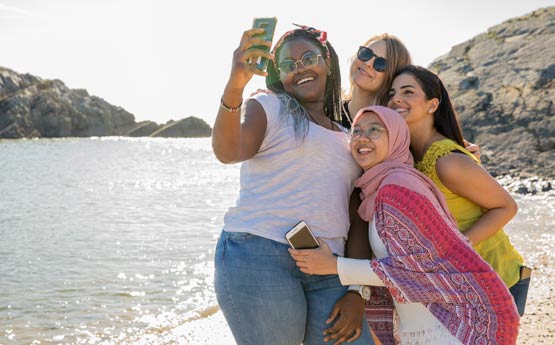 Four females on a beach taking a group selfie