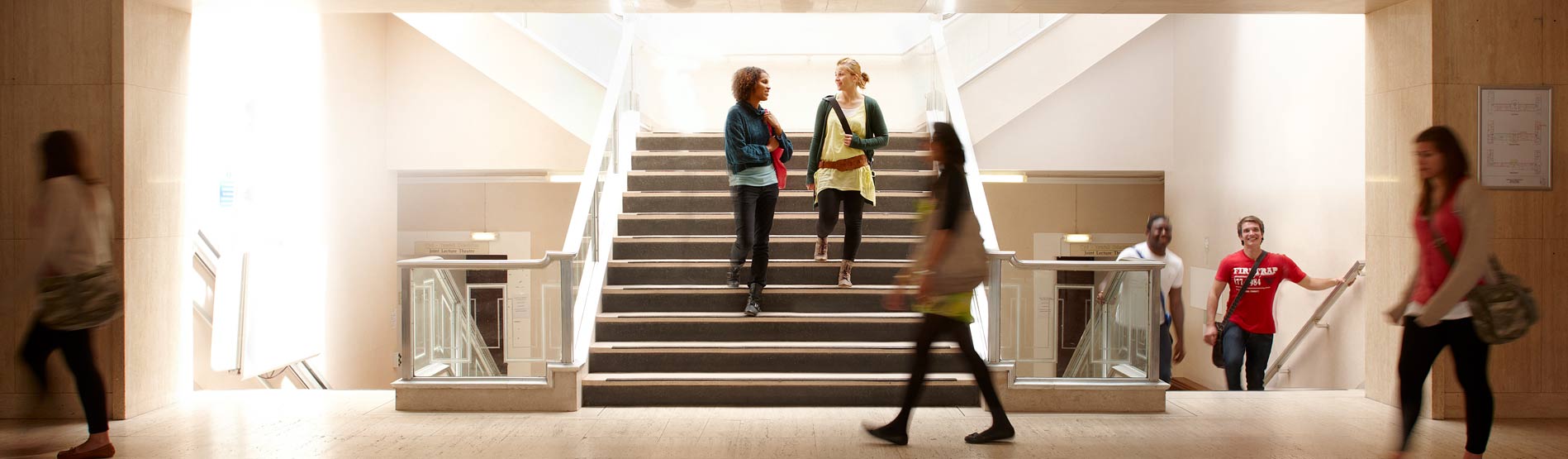 Students in the front foyer of Wallace, walking past and down the staircase.