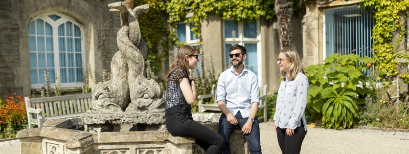 three postgraduate students sitting by a fountain