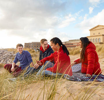 students sitting on the beach
