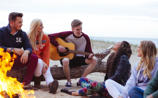Students playing guitar on the beach. 
