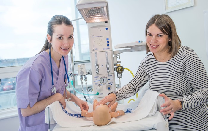 Student midwife Angharad Colinese, pictured during her training with lecturer Sophie Cunningham, who will be helping assist maternity services. Two people in a clinical setting with a baby mannekin.