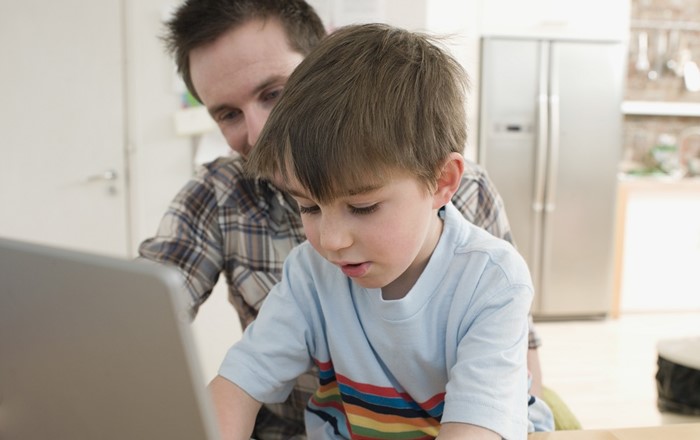 A boy at a computer with his father