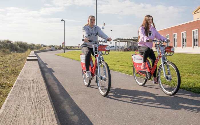 Two students ride on Santander cycles at the Bay Campus. 