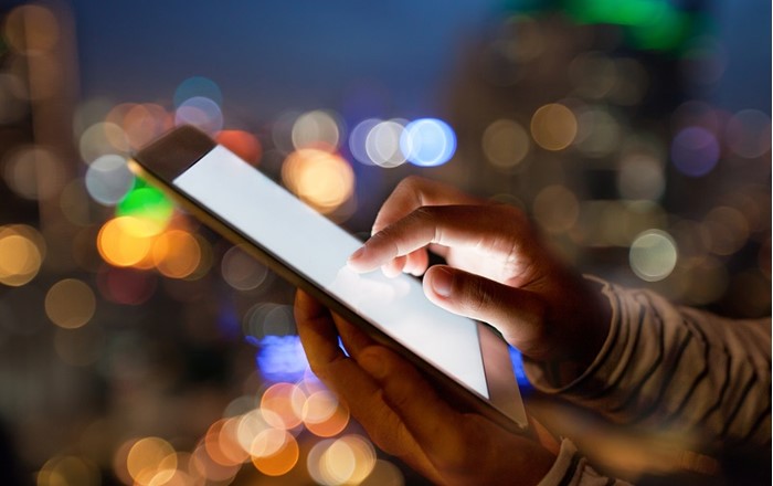 A hand touching a smartphone screen at night. How terrorist groups use social media, and how this can be countered, is the focus of a major international conference in Swansea
